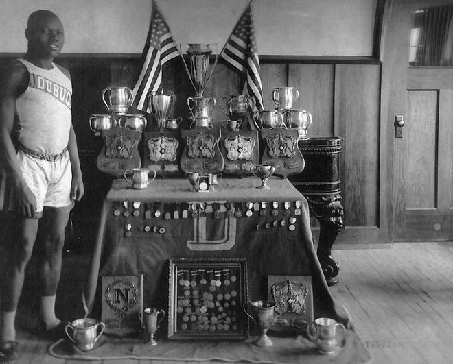 Solomon "Sol" Butler, a graduate of Hutchinson High School, poses with trophies and medals he won for athletic performances in college. [Courtesy University of Dubuque]
