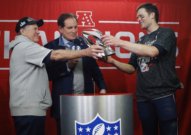Patriots head coach Bill Belichick, left, hands off the championship trophy to quarterback Tom Brady after defeating the Kansas City Chiefs in the AFC Championship Game.