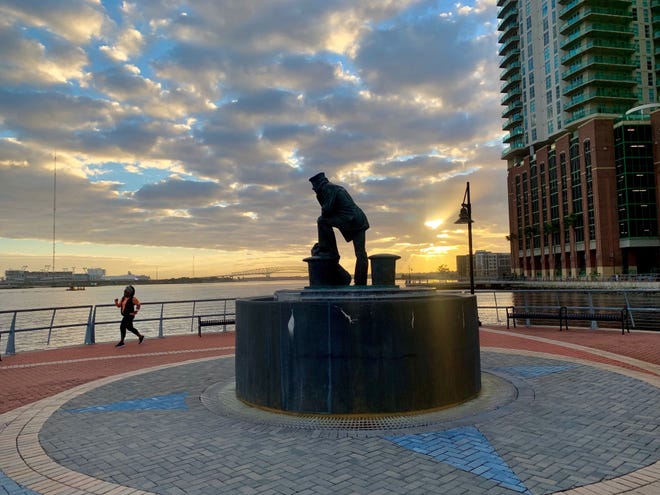 A walker passes the Lone Sailor statue on the Southbank Riverwalk shortly after sunrise on Wednesday. Times-Union columnist Mark Woods started this leg of a walk across Jacksonville at the boat ramp near River City Brewing. [MARK WOODS/FLORIDA TIMES-UNION]