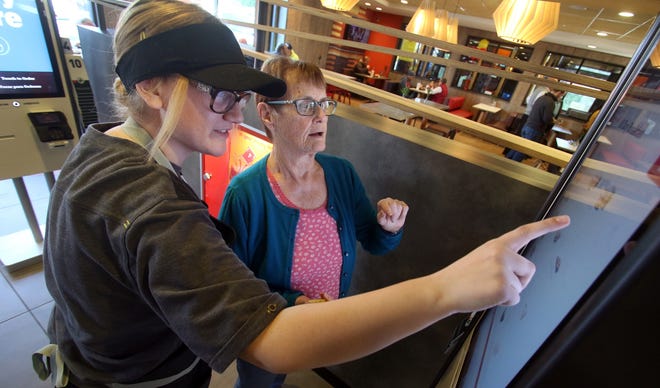 Employee Salem Napier helps customer Lois Bergman navigate one of the new kiosks inside the McDonald's on North Main Street in Belmont Friday morning, Jan. 25, 2019. [Mike Hensdill/The Gasston Gazette]