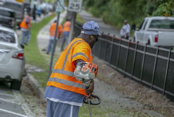 State prisoners work on the public spaces along Southwest 6th Avenue in October. City officials voted Thursday to end such contracts with the state's Department of Corrections within 30 days. [Alan Youngblood/Gainesville Sun]