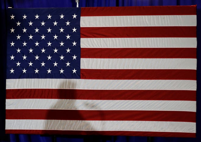 FILE - In this Aug. 31, 2018, file photo, President Donald Trump's shadow is shown on an American flag as he speaks before signing an executive order at the CPCC Harris Conference Center in Charlotte, N.C. A majority of Americans disapprove of the way President Donald Trump is handling U.S. foreign policy and about half think the country’s global standing will deteriorate during the next year, according to new poll about the state of the nation’s affairs with the world. (AP Photo/Chuck Burton, File)