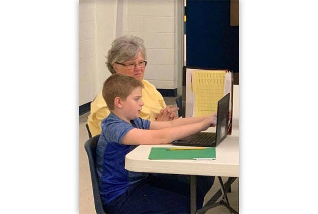 ‘MISS ANN’ — Ann Trogdon helps a child in the Trindale Elementary School Media Center where she volunteers. (Contributed)