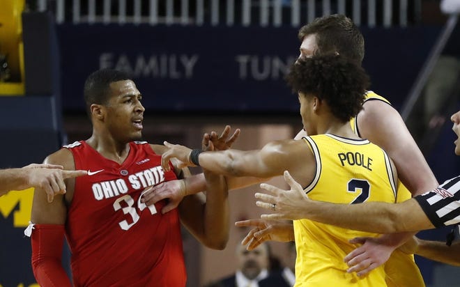 Michigan center Jon Teske pushes away Ohio State forward Kaleb Wesson while guard Jordan Poole (2) gestures during the second half of Tuesday night's game in Ann Arbor, Mich. [Carlos Osorio/The Associated Press]