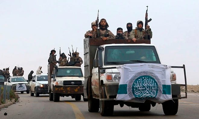 This photo released Dec. 4, 2018 by the al-Qaida-affiliated Ibaa News Agency, shows al-Qaida-linked fighters driving their vehicles during a military drill in northern Syria. It took the al-Qaida-linked militants only few days to capture more than two dozen towns and villages in and around Idlib province, cementing the group’s control over an area in northwestern Syria the size of neighboring Lebanon. The push by members of Hayat Tahrir al-Sham, or HTS, is the most serious blow to a September cease-fire for Idlib brokered by Russia and Turkey, and puts tens of thousands of civilians at risk of losing medical support due to a drop in aid from western agencies. (Ibaa News Agency, via AP)