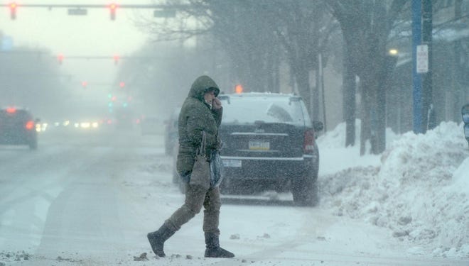 Blowing snow obscures a pedestrian at West Seventh and State streets in Erie, Pa. [JACK HANRAHAN/ERIE TIMES-NEWS]