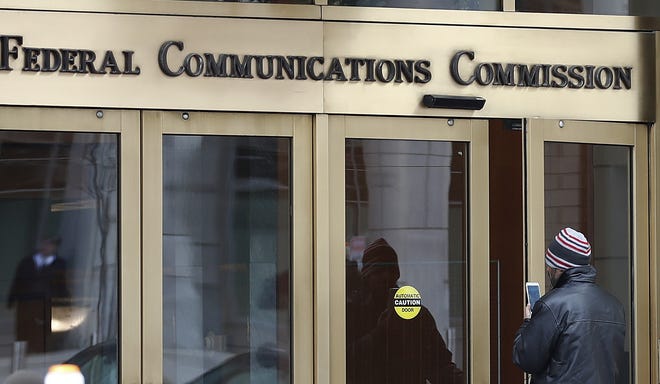 A person with a smartphone enters the Federal Communications Commission building in Washington. Tech companies and nearly two dozen U.S. states clashed with the government in federal court Friday over the repeal of net neutrality, a set of Obama-era rules aimed at preventing big internet providers from discriminating against certain technology and services. The action rolling back the neutrality rules "is a stab in the heart of the Communications Act," said attorney Pantelis Michalopoulos, referring to the Depression-era law that established the FCC. [CAROLYN KASTER/THE ASSOCIATED PRESS]
