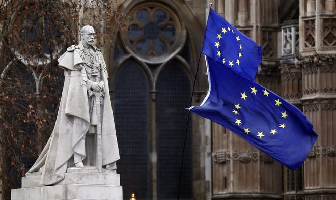 The EU flags wave next to a statue of King George V in Westminster, London, as British lawmakers struggle with a voter-mandated divorce from the European Union. [ASSOCIATED PRESS]