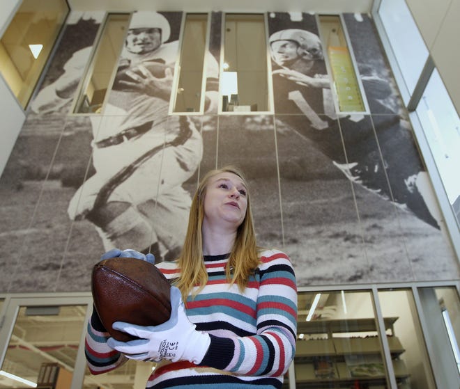 Rachel Knapp, curatorial assistant at the Pro Football Hall of Fame in Canton, holds a football that belonged to Phil Ragazzo, who played for the Cleveland Rams from 1938-1940.  [Karen Schiely/Beacon Journal/Ohio.com]