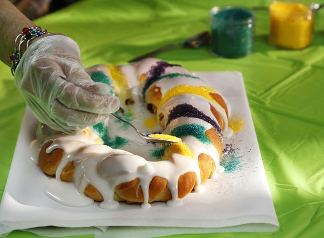 The traditional King Cake being iced. [Jim Beckel/The Oklahoman via AP]