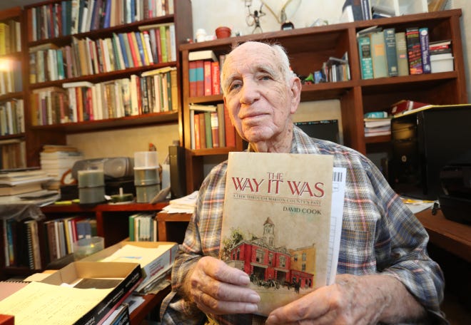 David Cook poses with "The Way It Was, A Trek Through Marion County's Past" at his home in Ocala. The book contains some of the columns he wrote for the Ocala Star-Banner, along with photos and personal anecdotes. His column writing dates back to 1953, when he penned "What's Cooking In Sports" for the Star-Banner. Cook was Editor In Chief of the Star-Banner from 1960-67, then became Assistant Editor of the Tallahassee Democrat. In 1979, he returned to the Star-Banner and began writing a column on nostalgia, which evolved into the historical "The Way It Was" columns. [Bruce Ackerman/Ocala Star-Banner]