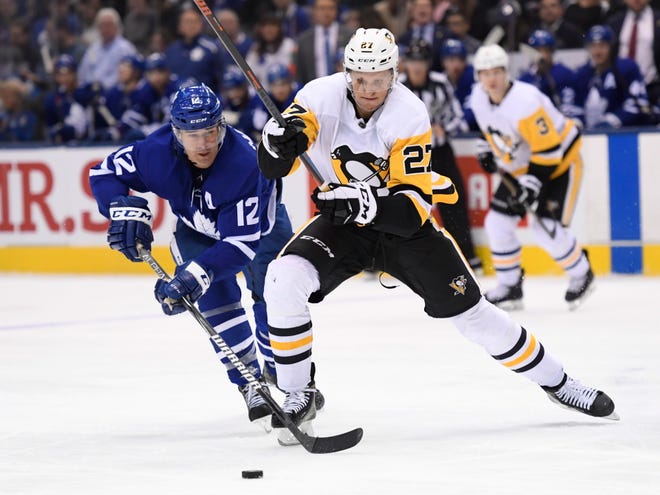 Toronto Maple Leafs center Patrick Marleau (12) and Pittsburgh Penguins center Nick Bjugstad (27) battle for the puck during the third period of an NHL hockey game, Saturday in Toronto. [Nathan Denette/The Canadian Press via AP]