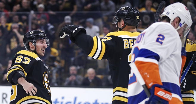 Bruins center Patrice Bergeron (center) is congratulated by teammate Brad Marchand after his goal during the second period of a game against the Islanders in Boston on Tuesday. The Bruins won 3-1. [AP Photo/Charles Krupa]
