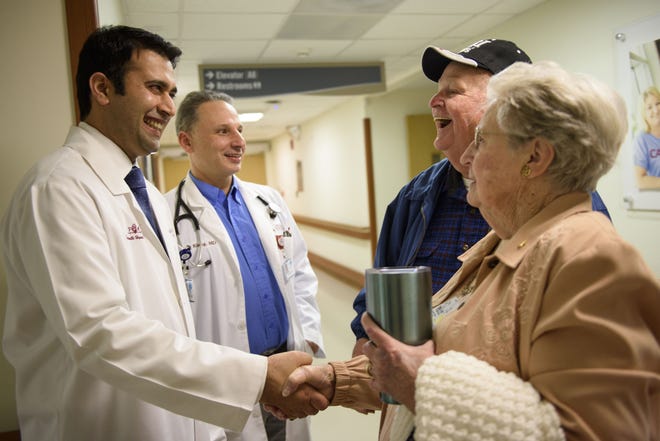 Dr. Amol Bahekar and Dr. Thor Klang, left to right, greet Leon Bradford and his wife, Nannie, before a checkup Jan. 23 at Cape Fear Valley Medical Center. Bradford was the first patient to have a heart valve replaced at the hospital with a procedure called Transcatheter Aortic Valve Replacement. [Melissa Sue Gerrits/The Fayetteville Observer]
