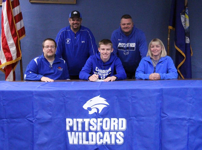 Pittsford´s Jake Burger (center) signs his letter of intent to play for Hillsdale College on Wednesday, joined by his father, Pittsford football coach Mike Burger (left), his mother, Kristy (right), and assistant football coaches Chris Hodos (back left) and T.G. Cook (back right). (JAMES GENSTERBLUM PHOTO)