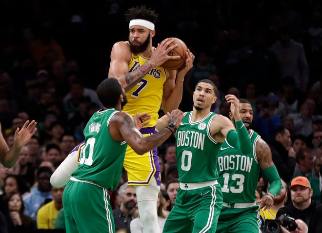 Los Angeles Lakers center JaVale McGee grabs a rebound over Celtics guard Kyrie Irving, left, forward Jayson Tatum and forward Marcus Morris. [The Associated Press]