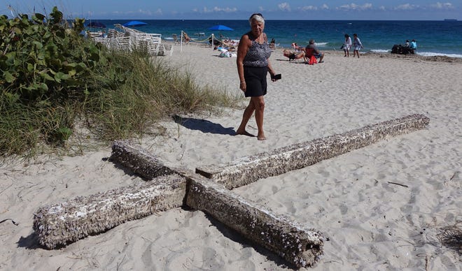 Aglair Rigos checks out a cross on the Galt Ocean Mile behind the Ocean Manor Beach Resort, in Fort Lauderdale, Fla., on Tuesday, Feb. 5, 2019. The large, barnacle-covered wooden cross washed ashore along the South Florida beach, captivating tourists who dragged it from the water’s edge. (Joe Cavaretta/South Florida Sun-Sentinel via AP)