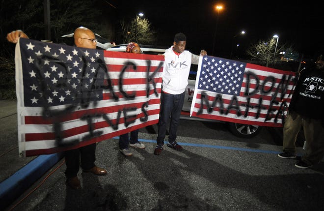 Activists protesting the police shooting of a black man in an Alabama shopping mall hold U.S. flags painted with the words "Black lives don't matter" in Hoover, Ala., Tuesday, Feb. 5, 2019. Demonstrators are upset with the state's decision against prosecuting a police officer who shot and killed Emantic "EJ" Bradford Jr. in a shopping mall on Thanksgiving night. [AP Photo/Jay Reeves]