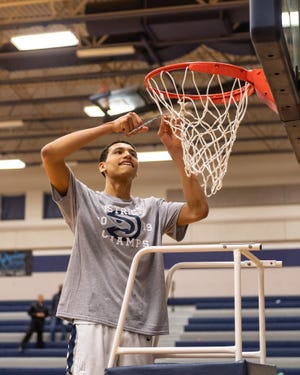 Dylan Disu starts cutting down the net as Hendrickson players celebrate their District 13-6A title. Hendrickson won a boys district basketball game 69-63 over Round Rock at home on Feb. 8. [Henry Huey for American-Statesman.]