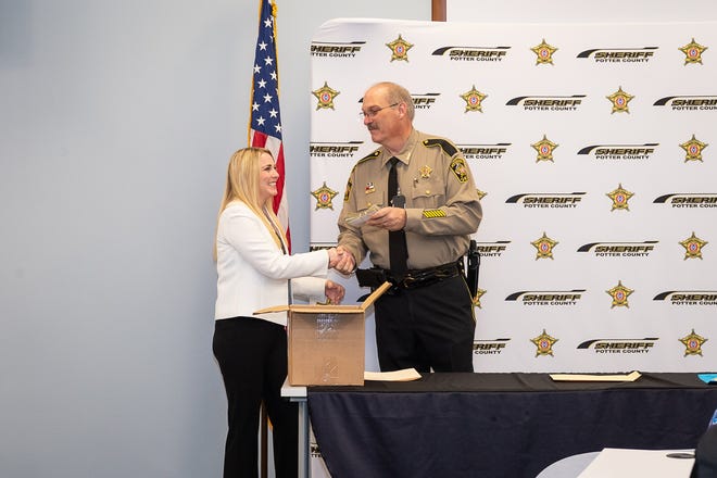 Potter County Sheriff Brian Thomas gives Wendi Swope a contribution of $1,280 for the First Responder Memorial Wall at the planned AJ Swope Plaza in downtown Amarillo February 8, 2019. [Shaie Williams for Amarillo Globe-News]