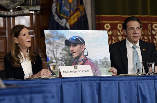 Linda Beigel Schulman, left, holds a photograph of her son Scott Beigel, who was killed during the Valentine's Day massacre at Marjory Stoneman Douglas High School, while speaking with New York Gov. Andrew Cuomo and gun safety advocates on Jan. 29 in Albany, N.Y. Since the shooting, states have seen a surge of interest in laws intended to make it easier to disarm people who show signs of being violent or suicidal. [AP Photo/Hans Pennink, File]