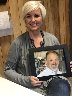 Tammy Pasour poses with a photograph of her late husband, Scott, while talking about holding a 35th anniversary celebration at the business he started, Pasour Auto Repair in Dallas. Scott Pasour died July 16, 2016, after getting struck by lightning. [PHOTO BY KEVIN ELLIS/THE GAZETTE]