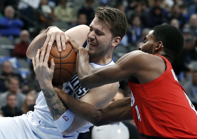 Dallas forward Luka Doncic hangs on to the ball as Portland's Maurice Harkless tries to rip it away during the Mavericks' victory Sunday. [Tony Gutierrez/The Associated Press]