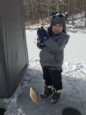 Cooper Marshall, 3, of New Philadelphia, shows off the bluegill he caught while ice fishing at Leesville Lake. Fishermen were able to find enough solid spots on area lakes to enjoy some winter fishing recently.