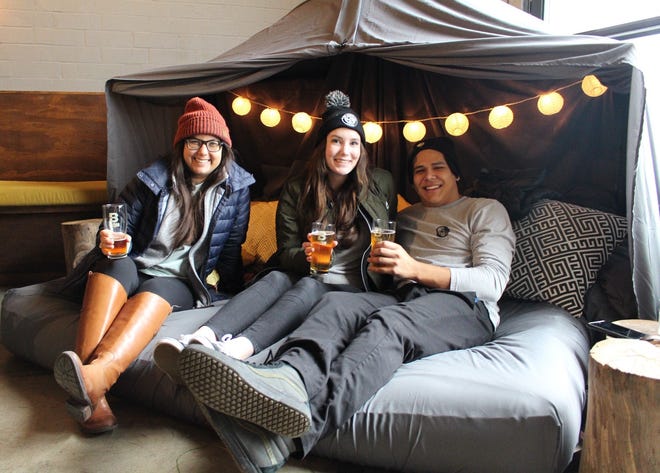 Friends Dianni Ortegon, Elizabeth Sweet and Jordan Fernandez relax together on the pillow fort at the Brewtorium, which created the lounge area in celebration of a new beer. [Arianna Auber / AMERICAN-STATESMAN]