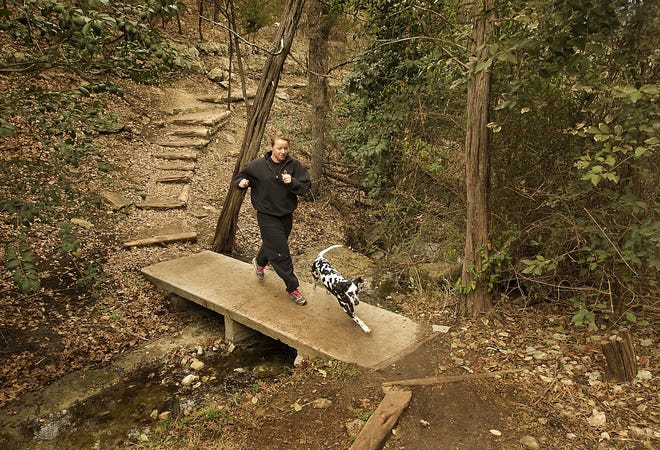 Molly Finnerty runs the lower trail with her dog Lilly on Jan. 31, 2014. The River Place Limited District is implementing a $10 fee per hiker and per pet starting March 2. RALPH BARRERA / AMERICAN-STATESMAN