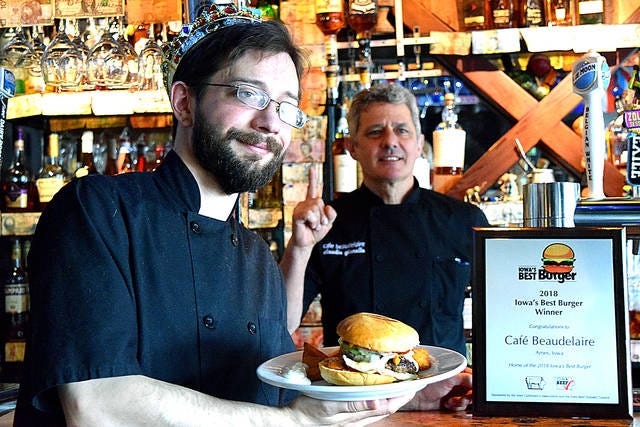 Cafe Beaudelaire kitchen manager Tom Otting, left, poses with a burger while owner Claudio Gianello, right, holds up a finger indicating the No. 1. The Campustown restaurant's burgers were named Iowa's best by the Iowa Cattlemen's Association in their annual contest in 2018. Ames Tribune file photo.