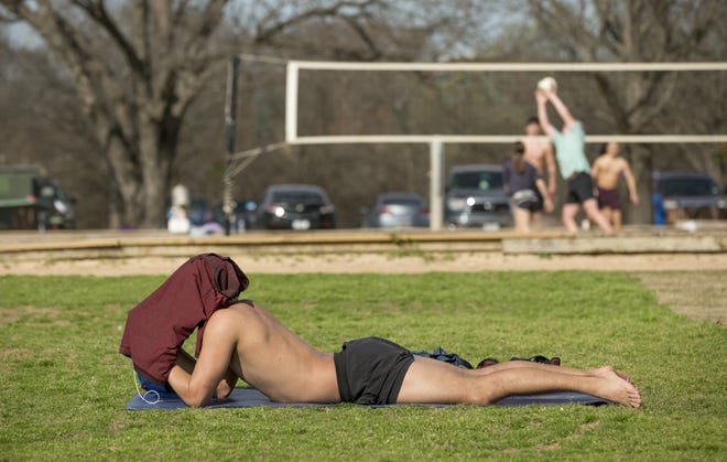 Albert Gomez looks at his cellphone screen in Zilker Park on Friday afternoon when temperatures hit a record high of 91 degrees. [JAY JANNER/AMERICAN-STATESMAN]