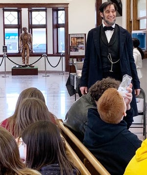 With the new "The Christening Lincoln" statue in the background students from New Holland-Middletown listen to Lincoln presenter Randy Duncan share stories of working the rider circuit in central Illinois. [Photo by Jean Ann Miller/The Courier]