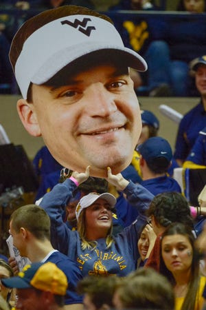 A Mountaineers fan holds aloft a large print cutout of the new WVU head football coach Neal Brown during the first half of an NCAA college basketball game in Morgantown, W.Va. on Saturday Feb. 9, 2019. (AP Photo/Craig Hudson)