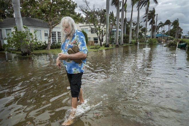 C.J. Johnson wades from his home on Marine Way after King Tides flooded the street and brought water into his home in Delray Beach, October 5, 2017. [GREG LOVETT/palmbeachpost.com]