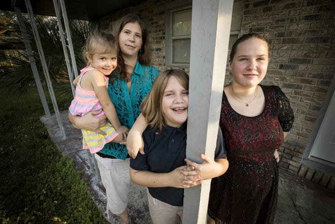 Charlene Cooper, left, holding her daughter Sara Monica, 4 ,with daughters Darcie,11, center, and Heather, 14, at their new home in Lakeland. Cooper was bordering on homelessness until she found assistance through Talbot House Ministries, which received a federal homeless assistance grant through the Homeless Coalition of Polk. [ ERNST PETERS/THE LEDGER ]