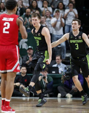 Michigan State's Matt McQuaid, center, and Foster Loyer celebrate as the Spartans pull away in the second half. At left is Ohio State's Musa Jallow. [Al Goldis/The Associated Press]