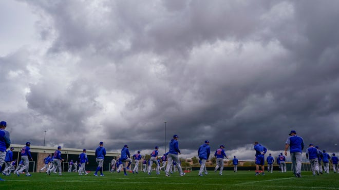 Chicago Cubs players stretch under a cloudy sky during a spring training baseball workout Monday, Feb. 18, 2019, in Mesa, Ariz. (AP Photo/Morry Gash)