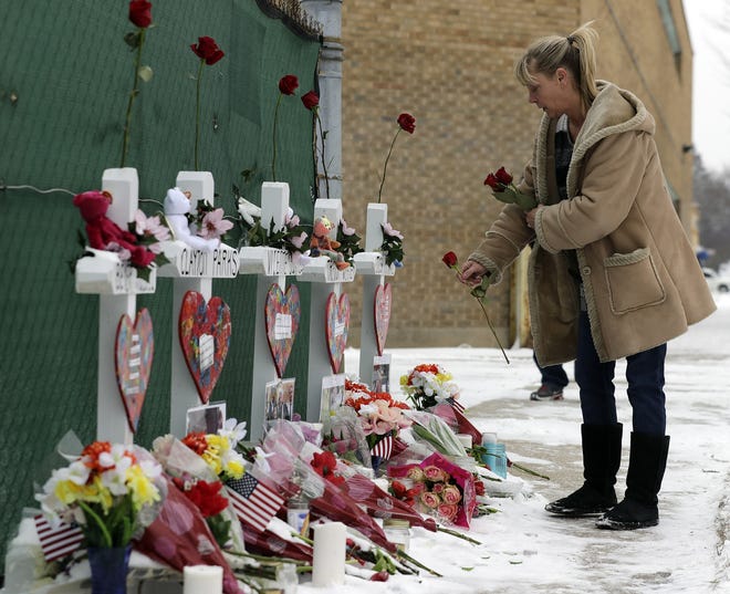A woman places flowers at a makeshift memorial Sunday in Aurora, Ill., near Henry Pratt Co. manufacturing company where five people and the shooter Gary Martin were killed Friday. Authorities say an initial background check five years ago failed to flag an out-of-state felony conviction that would have prevented Martin from buying the gun he used in the mass shooting. [AP Photo/Nam Y. Huh]