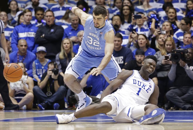 Duke's Zion Williamson (1) falls to the floor with an injury while chasing the ball with North Carolina's Luke Maye (32) during the first half of an NCAA college basketball game in Durham, N.C., Wednesday. [GERRY BROOME/AP PHOTO]