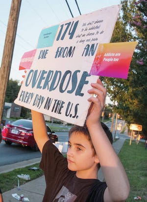 A SIGN OF SUPPORT — Gage Link-Hedrick, 12, of Asheboro, holds a sign as he stands along Salisbury Street in Asheboro during Overdose Awareness Day on Aug. 25, 2018. He has an uncle suffering from addiction. (Paul Church/The Courier-Tribune)