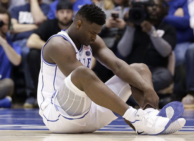 Duke's Zion Williamson sits on the floor after an injury during Wednesday night's game against North Carolina. Duke might have to figure out what the Zion Show will look like without its namesake, all because of a freak injury to arguably the most exciting player in college basketball. As his Nike shoe blew out, he hurt his right knee. [GERRY BROOME/THE ASSOCIATED PRESS]