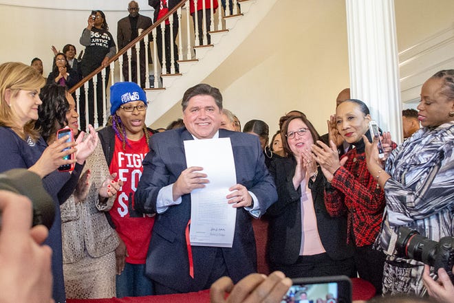 Gov. J.B. Pritzker signs Senate Bill 1 at the Governor’s Mansion on Tuesday in Springfield to increase the state’s minimum wage to $15 per hour over a six-year period.