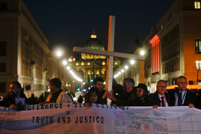 Survivors of sex abuse hold a cross as they gather in front of Via della Conciliazione, the road leading to St. Peter's Square, visible in background, during a twilight vigil prayer of the victims of sex abuse, in Rome, Thursday, Feb. 21, 2019 during a twilight vigil prayer near Castle Sant' Angelo, in Rome, Thursday, Feb. 21, 2019. Pope Francis opened a landmark sex abuse prevention summit Thursday by warning senior Catholic figures that the faithful are demanding concrete action against predator priests and not just words of condemnation. (AP Photo/Gregorio Borgia)