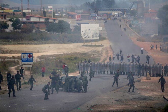 Venezuela's Bolivarian National Guard officers block the border between Brazil and Venezuela during clashes, Saturday, Feb.23, 2019. Tensions are running high in the Brazilian border city of Pacaraima. Thousands remained at the city's international border crossing with Venezuela to demand the entry of food and medicine. (AP Photo/Ivan Valencia)