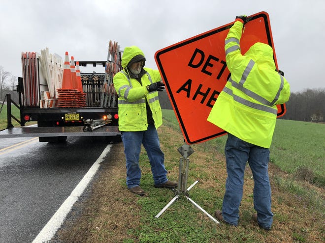 Workers with the North Carolina Department of Transportation place detour signs near Trent McSwain Road in Earl, which was closed Friday after a pipe washed out under the roadway. [Casey White/The Star]