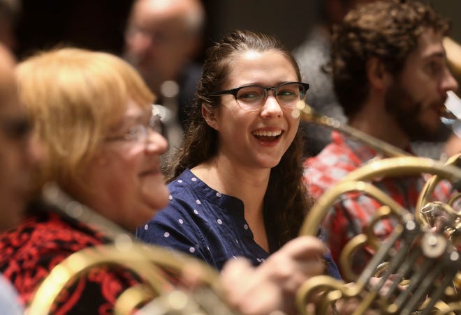 Carolyn Wahl, left, shares a smile with Kaitlyn Resler, who had her first rehearsal with the orchestra at the Mahaffey Theater in St. Petersburg. Resler, who is 23 and the newest member of the orchestra, now sits directly to the left of Wahl, 67, her former teacher who has been a horn player with TFO since the 1974 season, the longest run of any current musician. [Dirk Shadd/Tampa Bay Times via AP]
