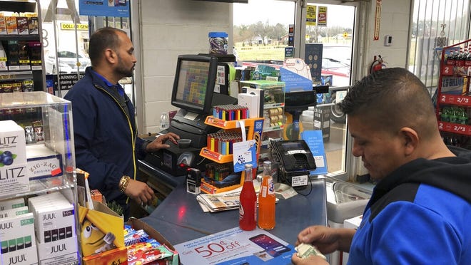 Jee Patel checks out a customer at the KC Mart on Tuesday, Feb. 19, 2019, in Simpsonville, South Carolina. The store sold the only Mega Millions ticket to win the $1.5 billion jackpot in October 2018. The ticket has not been claimed. (AP Photo/Jeffrey Collins)