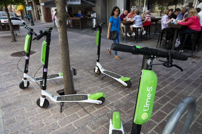 A woman walks past Lime-S scooters parked in downtown Austin in this photo from Aug. 8, 2018. [LYNDA M. GONZALEZ / AMERICAN-STATESMAN]
