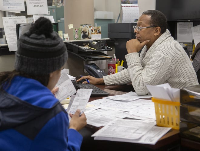 Kiona Stevens (left) has her city income tax prepared free by Richard C. Burton Jr. a tax auditor / collector for the Canton City income tax department. Because Canton's income tax rate rose from 2 to 2.5 percent in July, the 2018 personal return has two time periods - making filing this year more complicated. (CantonRep.com / Bob Rossiter)